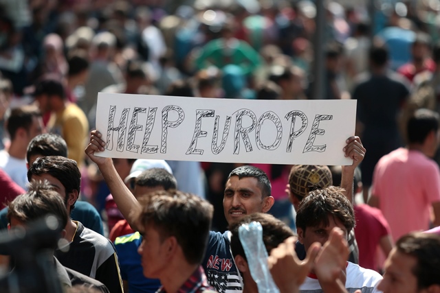 a man hold a placard reading quot help europe quot as syrian and afgan refugees attend a protest rally to demand to travel to germany photo afp