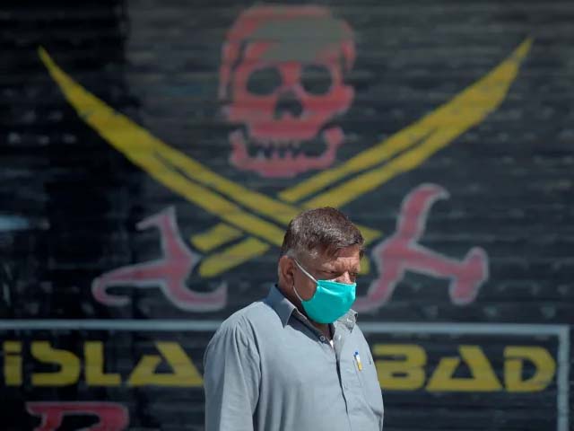 a pakistani man wearing a face mask walks past closed market shops in karachi photo getty