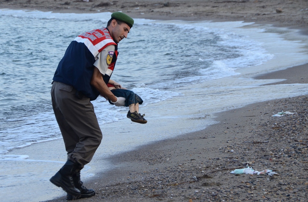 a turkish police officer carries a migrant child 039 s dead body off the shores in bodrum southern turkey on september 2 2015 after a boat carrying refugees sank while reaching the greek island of kos photo afp