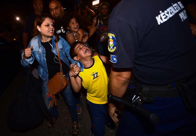 a migrants family is escorted by police from bicske train station to a bus that wil take them into a refugee camp after their train from budapest was stopped here on september 3 2015 photo afp