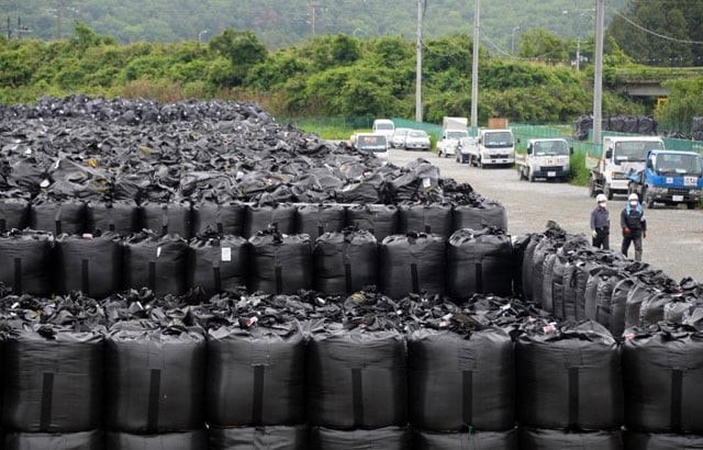 workers walk beside bags of contaminated earth at a collection site in naraha town in fukushima prefecture on june 13 2013 photo afp workers walk beside bags of contaminated earth at a collection site in naraha town in fukushima prefecture on june 13 2013 photo afp