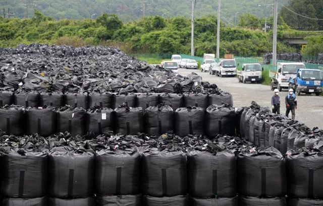 workers walk beside bags of contaminated earth at a collection site in naraha town in fukushima prefecture on june 13 2013 photo afp workers walk beside bags of contaminated earth at a collection site in naraha town in fukushima prefecture on june 13 2013 photo afp