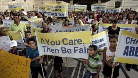 hundreds of arab israeli christians hold banners in a rally against what they said was state discrimination in funding their schools at the foot of the basilica of the annunciation in nazareth on sep 1 2015 photo afp