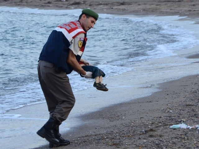 a turkish police officer carries a migrant child 039 s dead body off the shores in bodrum southern turkey on september 2 2015 after a boat carrying refugees sank while reaching the greek island of kos photo afp