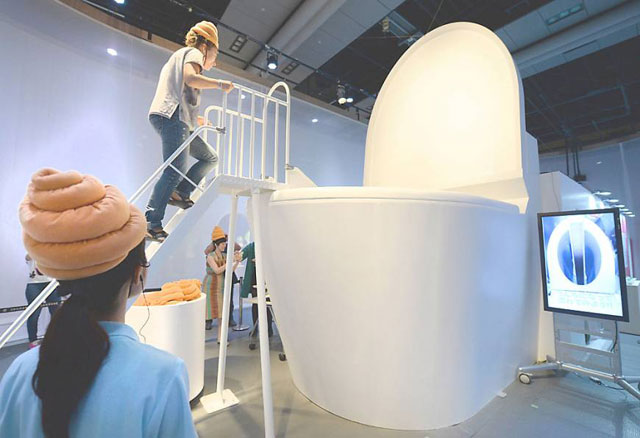 a woman climbs stairs to ride a giant toilet slide during an exhibition at the national museum of emerging science and innovation in tokyo in july 2014 photo afp