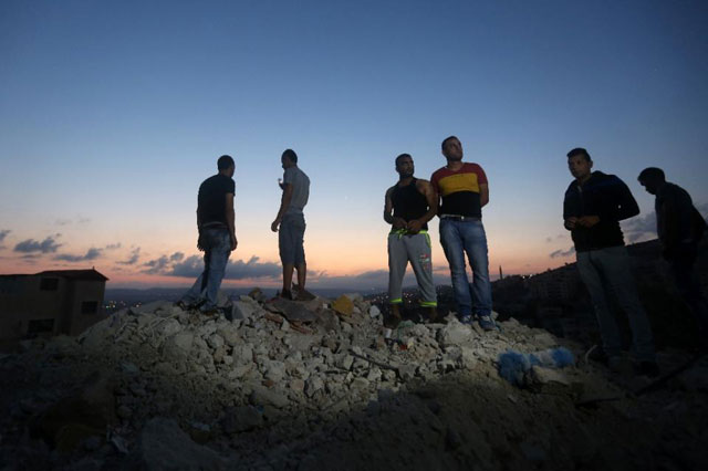 palestinians stand on the rubble of a house which was demolished by israeli security forces during an overnight raid in the west bank city of jenin on september 1 2015 photo afp