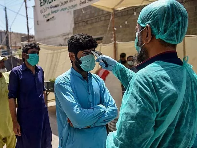 a municipal worker checks the body temperature of a man queuing at a food distribution point photo getty a municipal worker checks the body temperature of a man queuing at a food distribution point photo getty