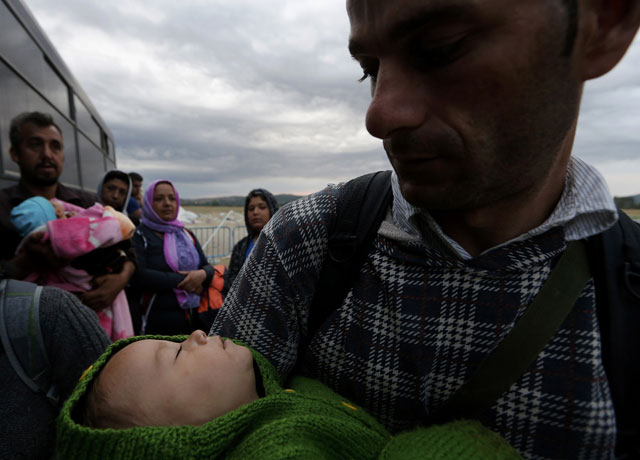 syrian refugee father tries to keep his baby son warm while waiting by a police bus to cross greece 039 s border with macedonia near the greek village of idomeni september 8 2015 photo reuters