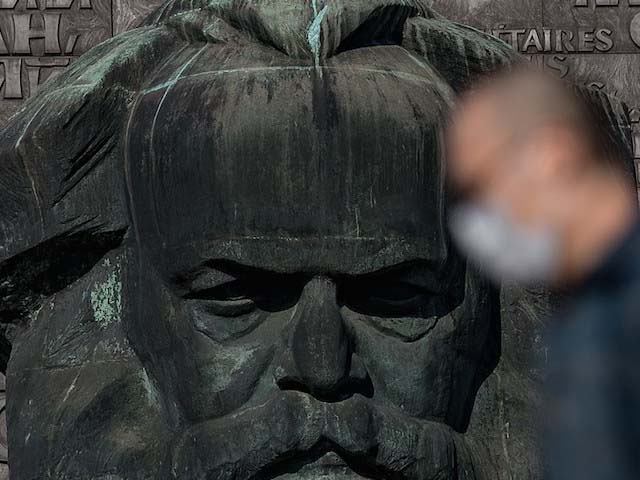 a man wearing a face mask passes the karl marx monument in the centre of chemnitz photo getty