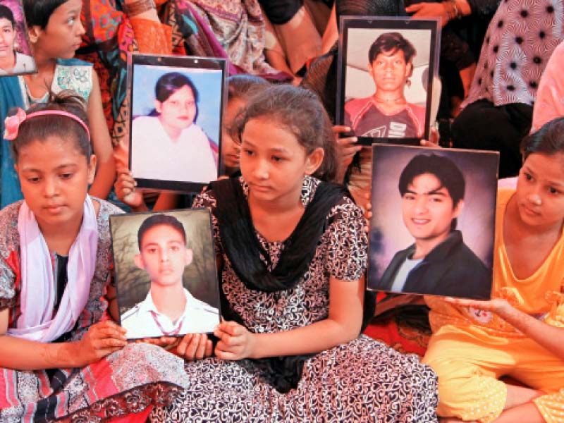relatives hold photos of the victims of the baldia factory fire tragedy on friday as they marked three years of the tragedy at the site of the ill fated factory photo aysha saleem express