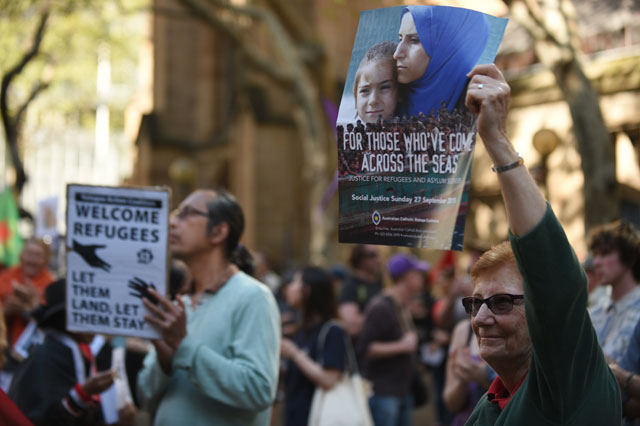protesters hold up placards in support of migrant refugees at a rally in sydney on september 12 2015 photo afp