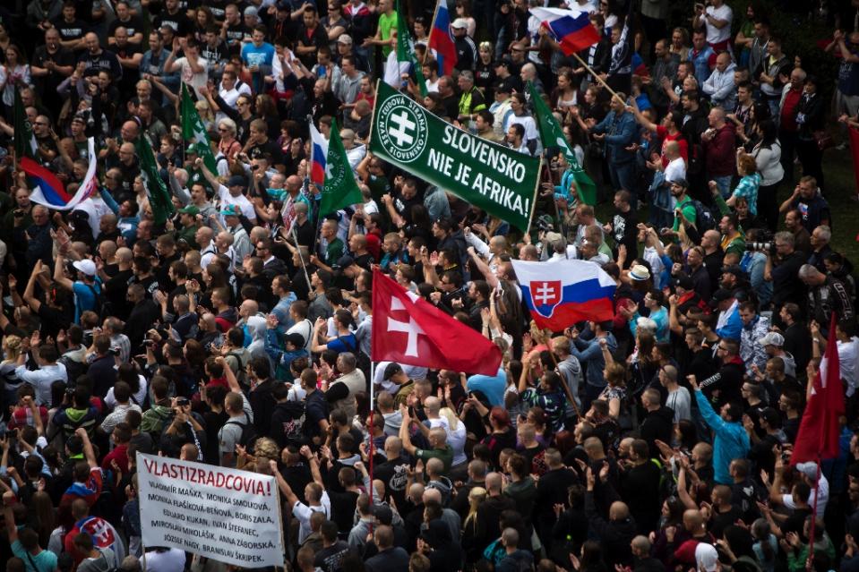 participants wave flags and hold a banner reading quot slovakia is not africa quot during an anti immigration rally on june 20 2015 in bratislava slovakia photo afp