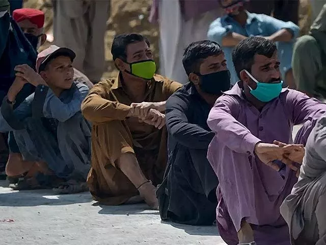 people sit in a line to receive free food donations in karachi photo afp people sit in a line to receive free food donations in karachi photo afp