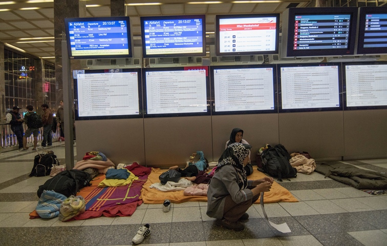 migrants sit at the far end of a platform at vienna 039 s train station westbahnhof in vienna on september 13 2015 austria 039 s state owned rail company announced sunday it will suspend train services with germany as europe tries to cope with a massive surge of refugee arrivals the announcement came as germany said it was reinstating quot temporary quot controls at the border with austria photo afp