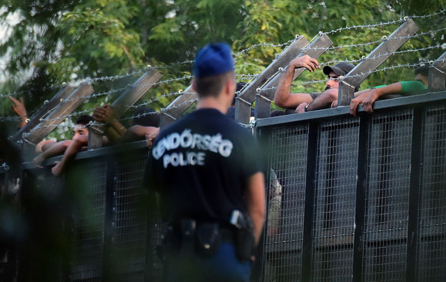 hungarian police officers stand on guard in front of a metal gate at the closed m5 highway to block circulation of migrants at the hungarian serbian border near roszke station on september 15 2015 after the hungarian government established a new border protection law photo afp