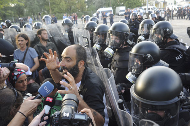 a migrant talks to the media in front of hungarian riot police at the border crossing with serbia in roszke hungary september 16 2015 hungarian police fired tear gas and water cannon at protesting migrants demanding they be allowed to enter from serbia on wednesday on the second day of a border crackdown photo reuters