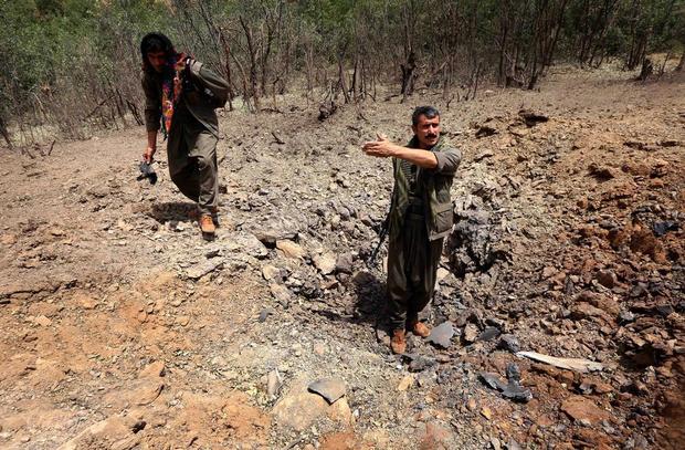 a file photo shows members of the pkk inspect a crater reportedly caused by an airstrikes by turkish warplanes photo afp