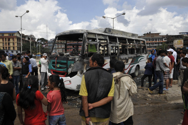 nepalese bystanders gather around the charred remains of a bus which was set alight during a general strike call by the hardline breakaway faction of former maoist rebels communist party of nepal maoist in kathmandu on september 20 2015 photo afp nepalese bystanders gather around the charred remains of a bus which was set alight during a general strike call by the hardline breakaway faction of former maoist rebels communist party of nepal maoist in kathmandu on september 20 2015 photo afp