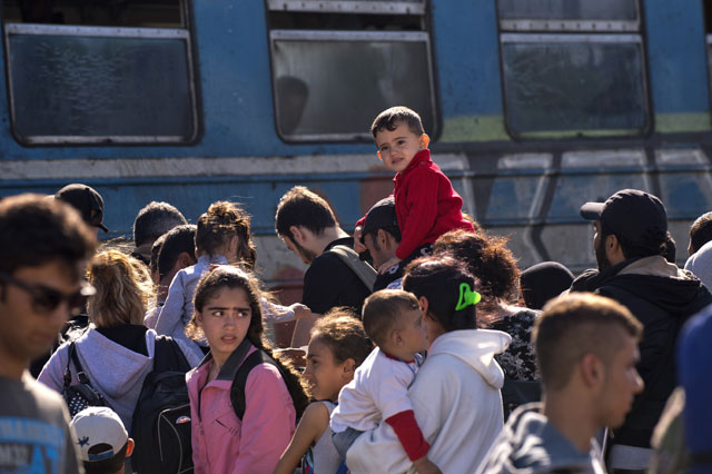 migrants and refugees queue to board a train heading to serbia near the town of gevgelija on the border between greece and macedonia on september 21 2015 eastern european ministers are due to gather to once again voice their opposition to compulsory migrant quotas as countries creaking under the strain of a steady stream of refugees struggle to agree on common action photo afp