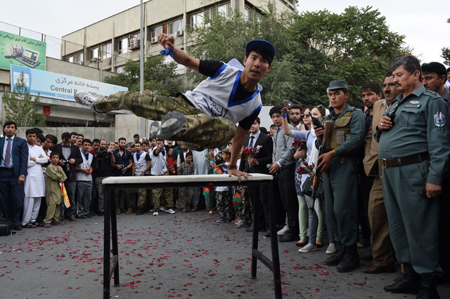 an afghan practitioner of parkour demonstrates his skills as spectators watch during a street concert to campaign for peace in the city of kabul on september 21 2015 photo afp