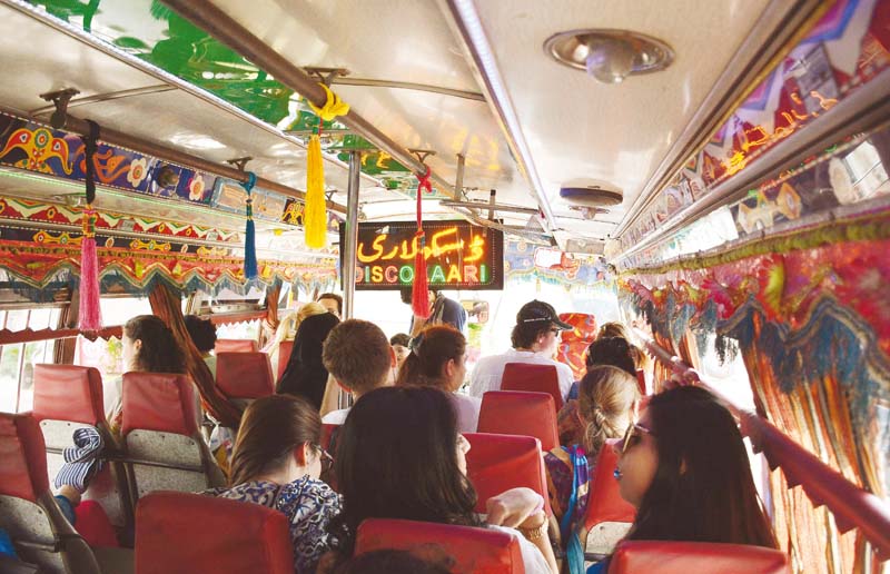 the full sized open bus decorated with rainbow lights and multicoloured bunting hanging from the ceiling photos huma choudhary