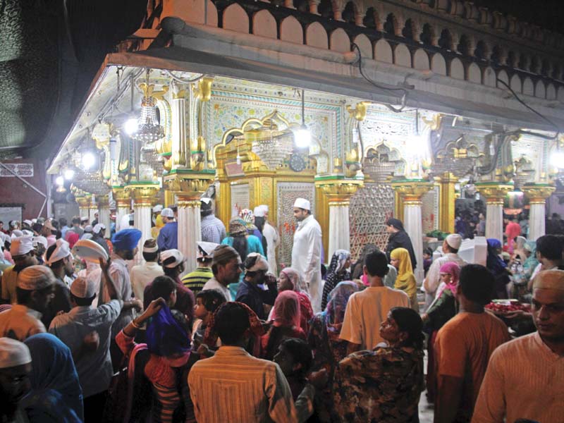 hundreds of devotees emerge from the doorway to the place that symbolises humanity and tolerance