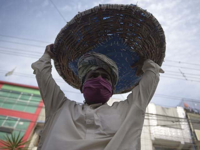 a labourer wearing a face mask carries his basket as he searches for customers photo afp