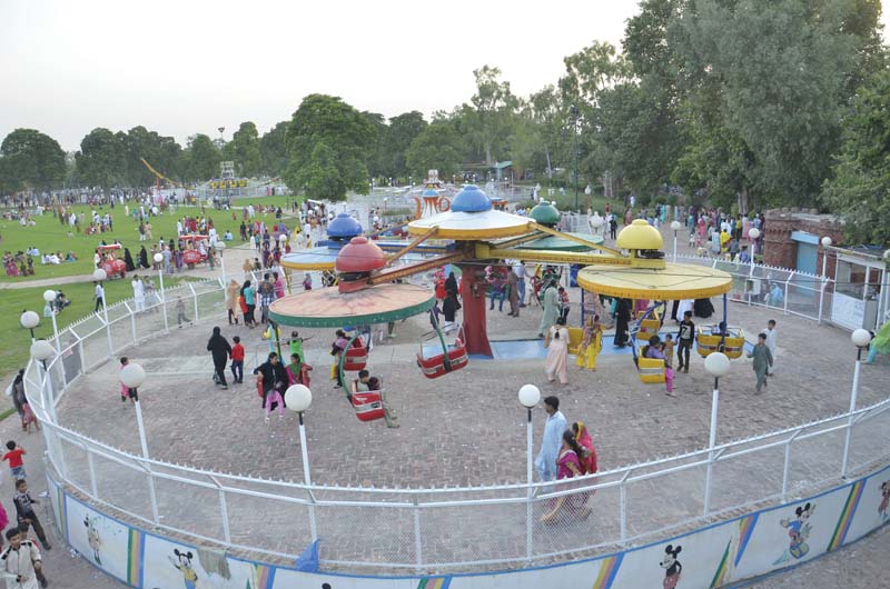 a large crowd is seen at the entrance of lahore zoo top children enjoy rides at a amusement park in allama iqbal town photos abid nawaz express