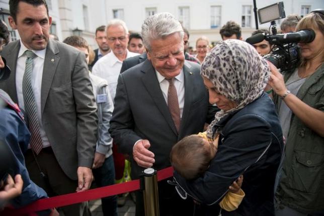 german president joachim gauck c talks to a migrant mother with her baby as he visits an asylum seekers accommodation facility in berlin germany on august 26 2015 photo reuters