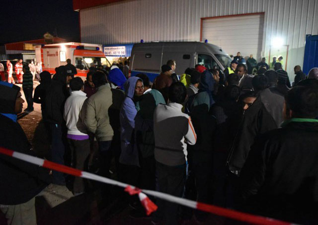 refugees stand by rescuers and police officers outside a migrants shelter in calden near kassel on september 27 2015 where clashes erupted between hundreds of occupants photo afp