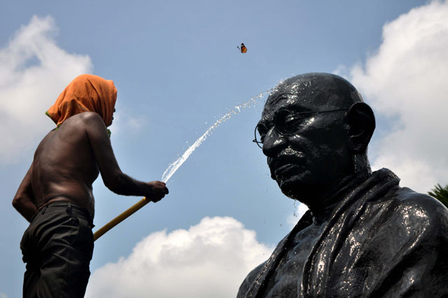 a butterfly flutters as an indian labourer showers water onto a statue of mahatma gandhi on the eve of gandhi jayanti at gandhi park in the eastern city bhubenaswar on october 1 2015 gandhi jayanti is also observed as international day of non violence and is celebrated in india to mark the occasion of the birth anniversary of mahatma gandhi photo afp