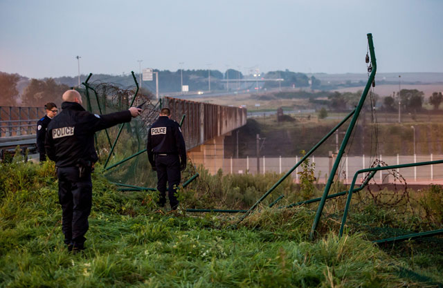 security agents stand in front of a damaged fence after migrants entered the eurotunnel site in coquelles northern france on october 3 2015 photo afp