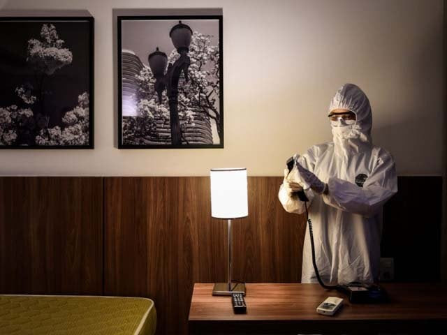 a member of the cleaning team disinfects a room at a hotel photo afp