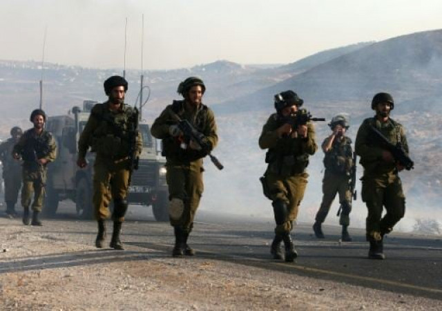 an israeli soldier aims his weapon at palestinian protesters during clashes on a street leading to duma village on august 1 2015 photo afp an israeli soldier aims his weapon at palestinian protesters during clashes on a street leading to duma village on august 1 2015 photo afp