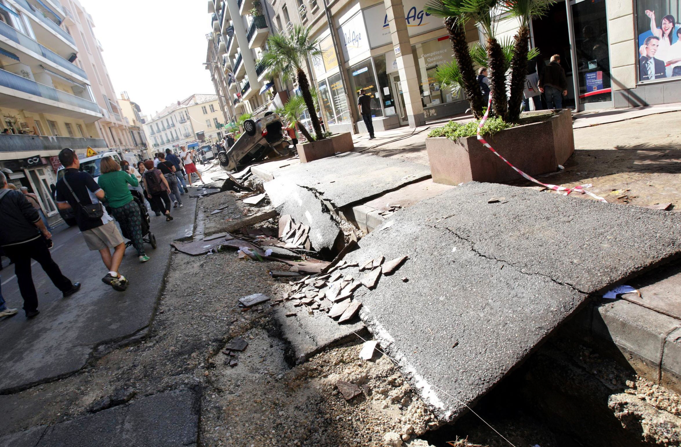 people walk in a damaged street in downtown cannes southeastern france on october 4 2015 after violent storms and floods struck the french riviera overnight killing at least 16 people with four others missing french authorities said photo afp