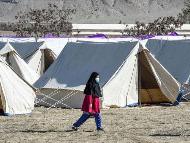 a pilgrim wearing a facemask walks beside tents at a quarantine camp in taftan photo afp