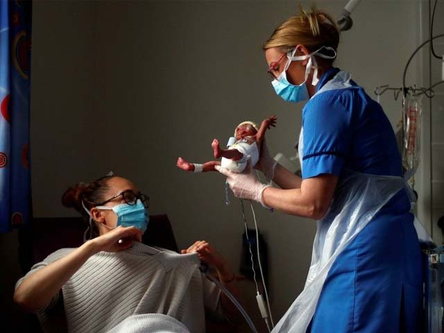 a nurse carries a premature baby to his mother photo afp a nurse carries a premature baby to his mother photo afp