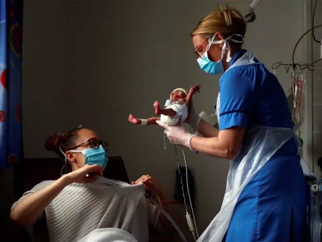 a nurse carries a premature baby to his mother photo afp a nurse carries a premature baby to his mother photo afp