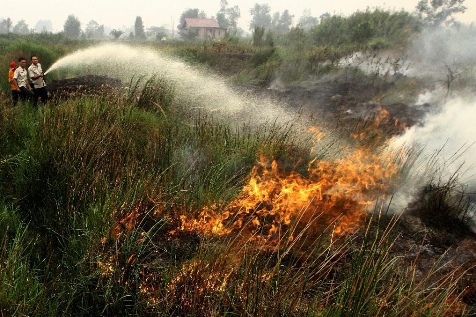 men use a hose to put out a fire in banyuasin indonesia on october 7 2015 photo afp