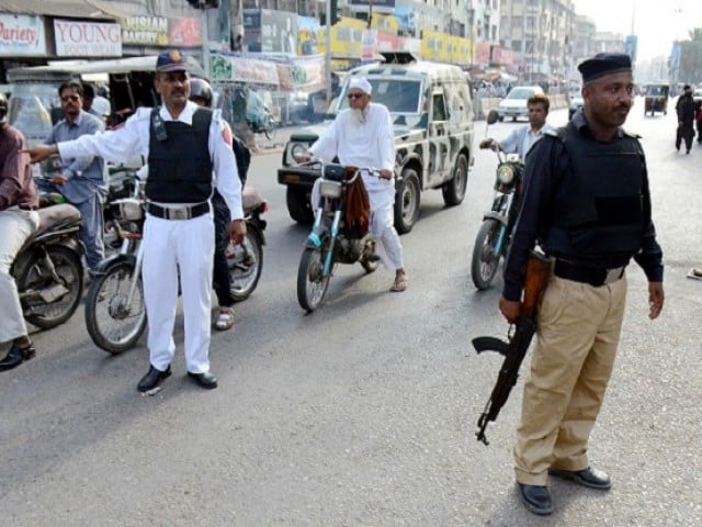 in this file photo a police commando provides security to a traffic police constable maintaining the flow of vehicular traffic in karachi photo inp