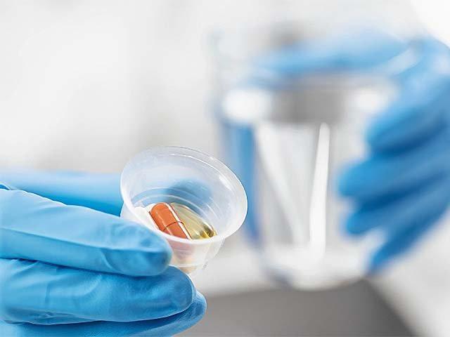 a doctor holding a graduated medicine cup full of pills photo afp