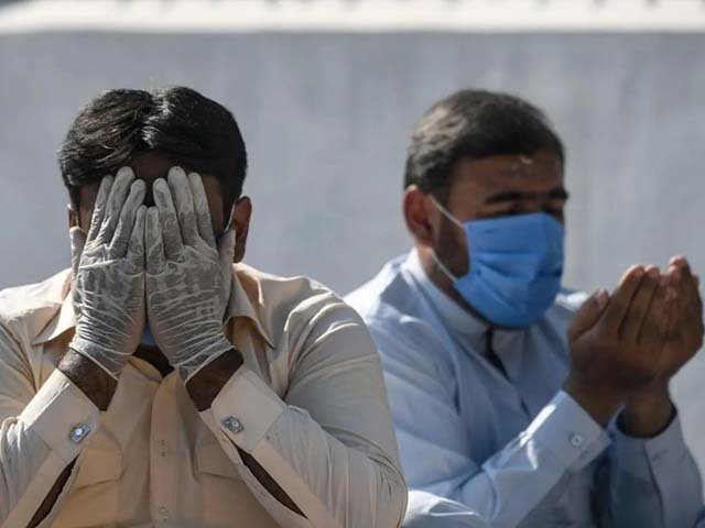 a man wearing a facemask and hand gloves offers prayers in rawalpindi photo afp