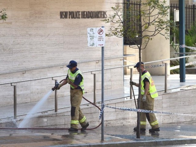 a fireman hoses down the scene where a 15 year old gunman shot dead a civilian police employee the previous day before being himself gunned down by police in sydney on october 3 2015 photo afp