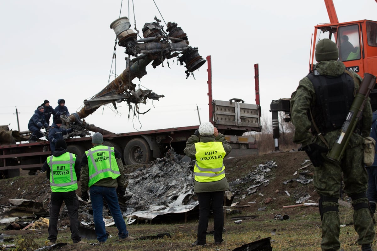 members of the dutch export team watch as parts of the wreckage of the malaysia airlines flight mh17 are removed and loaded on a truck at the crash site near the village of grabove in eastern ukraine on november 16 2014 photo afp