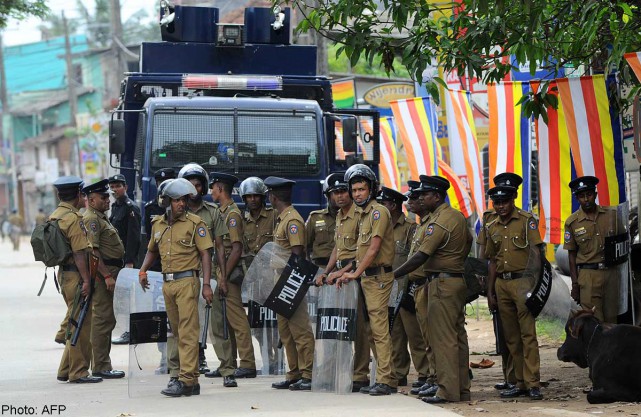 sri lankan police stand guard by a roadside following clashes between muslims and an extremist buddhist group in the town of alutgama on june 16 2014 photo afp