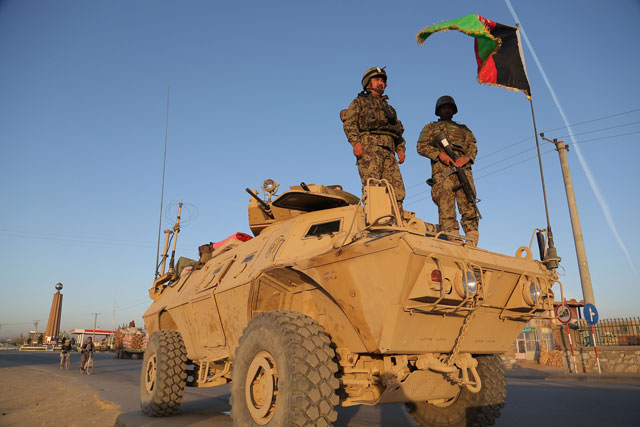 afghan security personnel stand guard on an armoured vehicle at a checkpoint in ghazni on october 13 2015 photo afp