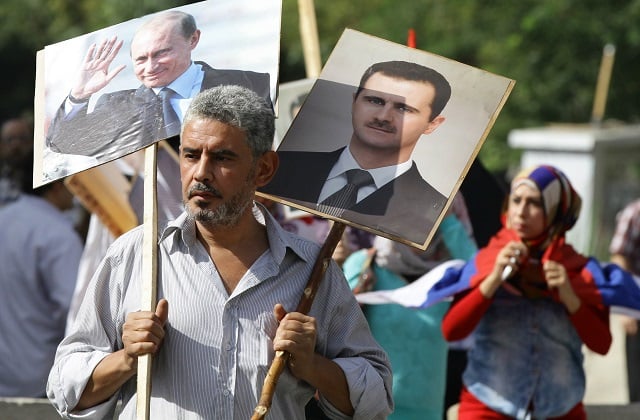 a syrian man holding up portraits of president bashar al assad and his russian counterpart valdimir putin l joins several hundred people who gathered near the russian embassy in damascus on october 13 2015 to express their support for moscow 039 s air war in syria just before two rockets struck the embassy compound sparking panic among the crowd photo afp