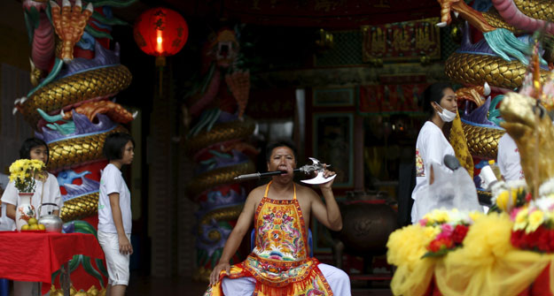 a devotee of the chinese bang neow shrine sits with an axe pierced through his cheek during a procession celebrating the annual vegetarian festival in phuket thailand october 18 2015 the festival featuring face piercing spirit mediums and strict vegetarianism celebrates the local chinese community 039 s belief that abstinence from meat and various stimulants during the ninth lunar month of the chinese calendar will help them obtain good health and peace of mind photo reuters