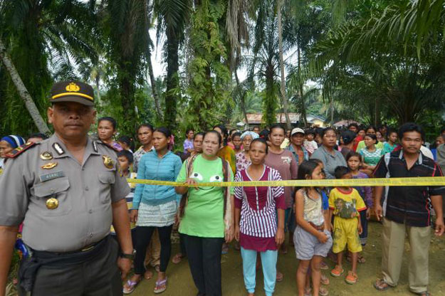 residents look on as a policeman stands guard in suka makmur village in singkil district indonesia aceh province october 14 2015 in this picture taken by antara foto photo reuters