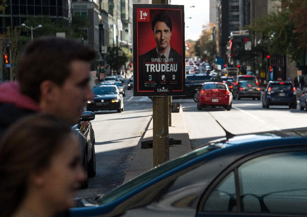 people walk past a poster for canadian liberal party leader justin trudeau in montreal on october 17 2015 photo afp